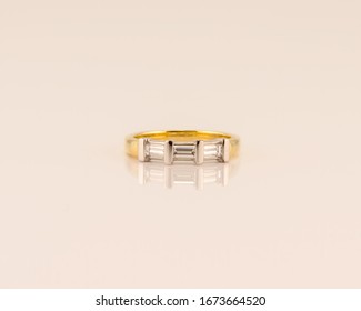 A modern diamond wedding band created with three baguette diamonds set in yellow gold, isolated on a white background