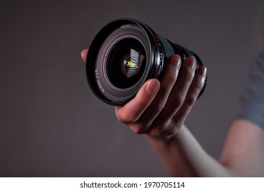 Modern digital camera lens in hand close up over dark background.