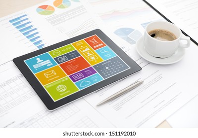 Modern digital tablet with colorful modern widows user interface on a screen lying on a desk with some papers and documents, pen and cup of coffee.