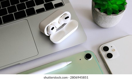 Modern digital workspace featuring wireless earbuds, laptop, tablet, smartphone and stylus pen on a clean white desk. Ideal for technology, mobile devices, remote work, productivity, online communication and digital lifestyle concepts.