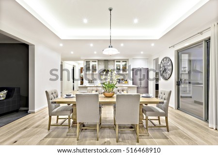 Modern dining room with hanging lamps on, there are chairs and table setup with fancy items on the wooden floor