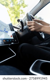 Modern driver using GPS navigation on a large touchscreen in a high-tech electric vehicle. Concept of smart mobility, urban commuting, and future automotive technology. Vertical Shot