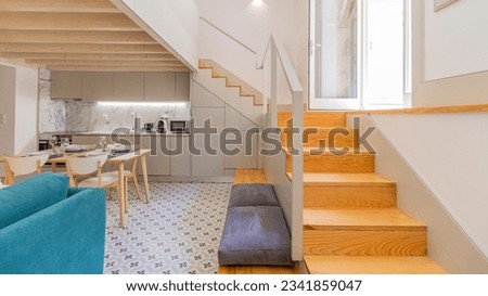 Modern duplex with kitchen under the stairs leading to the master bedroom. White interior design with wood tones and plenty of storage.