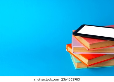 Modern e-book on stack of hardcover books on blue background - Shutterstock ID 2364563983
