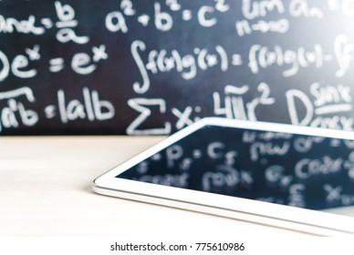 Modern education and e learning concept. Tablet in front of a blackboard full of writing at school. Smart mobile device and chalkboard in classroom. Learning with technology. Digital exam. - Powered by Shutterstock