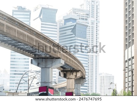 A modern efficient integrated transport network,running atop tall concrete pillars,winding in between modern skyscrapers,connecting many areas of central KL City and its International airport.