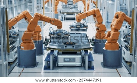 Modern Electric Car Automated Smart Factory. EV Battery Pack Production Line Equipped with Orange Advanced Robot Arms Row of Robotic Arms inside Bright Plant Assemble Batteries for Automotive Industry