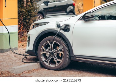 A Modern Electric Car Is Charged In The Parking Lot. Environmental Awareness And Green Transport And The Transition To Renewable Energy Sources