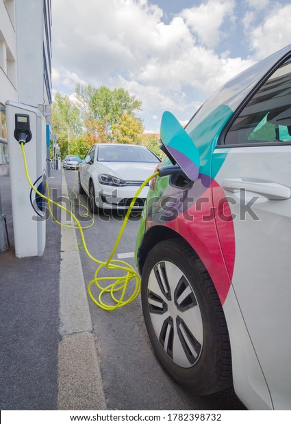 Modern electric car plugged in charging on the\
street station. New energy vehicles, environment friendly\
alternative energy for\
cars
