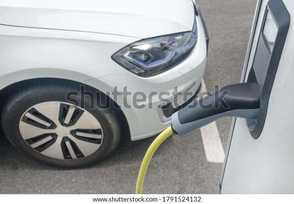 Modern electric car plugged in charging on the\
street station. New energy vehicles, environment friendly\
alternative energy for\
cars