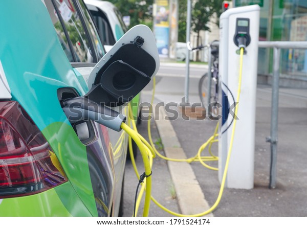 Modern electric cars plugged in charging on the\
street station. New energy vehicles, environment friendly\
alternative energy for\
cars
