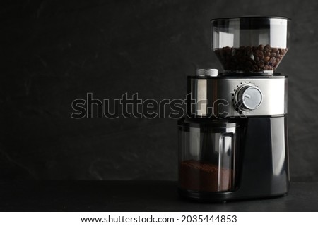 Modern electric coffee grinder on black table. Space for text