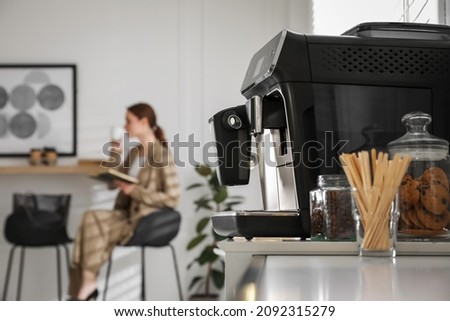 Modern electric coffee machine on table in office. Space for text