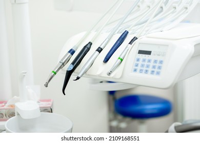 Modern electric dentist tools, burnisher, drill, turbine, handpiece included in main unit of dentist chair near cuspidor at dentist office. Dentistry, medical equipment, stomatology concept. Close up.