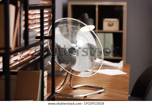 Modern electric fan on\
table in office