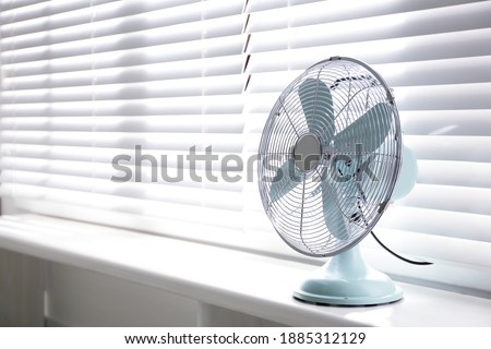 Modern electric fan on window sill indoors. Space for text