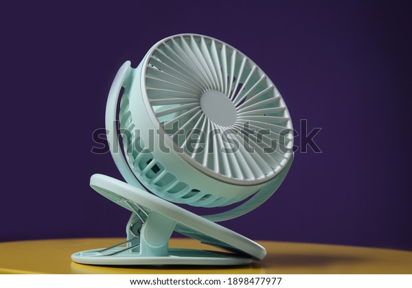 Modern electric fan on yellow table against\
violet background