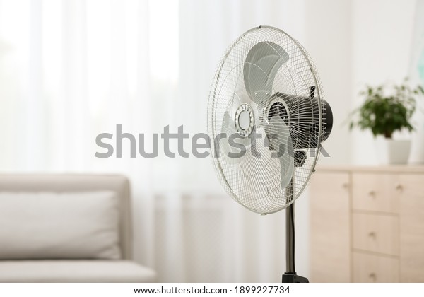 Modern electric fan\
in room. Space for text