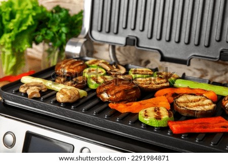Modern electric grill with tasty vegetables on table, closeup