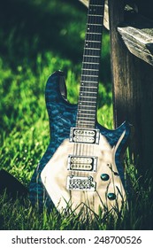 Modern Electric Guitar At Countryside Place. Wooden Fence And Summer Grass. Country Music Theme.