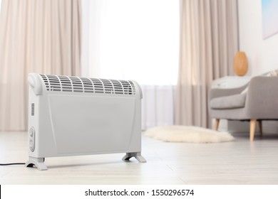 Modern electric heater on floor at home. Space for text
