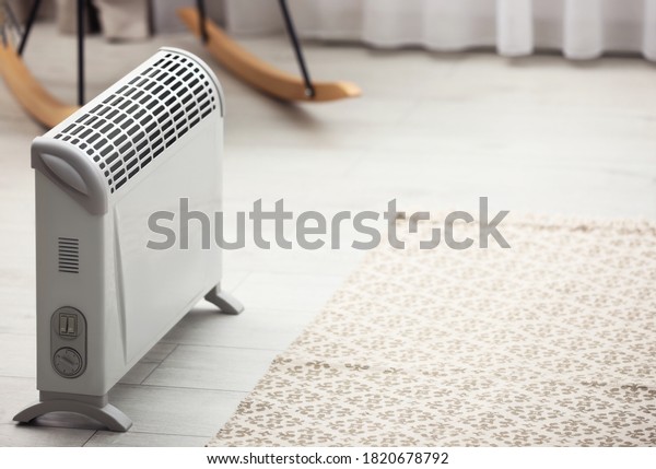 Modern electric heater in stylish room interior.\
Space for text