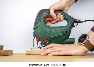 Modern Electric Jig Saw Tool In A Hand For DIY Home Woodworking. Wood Boards On Background