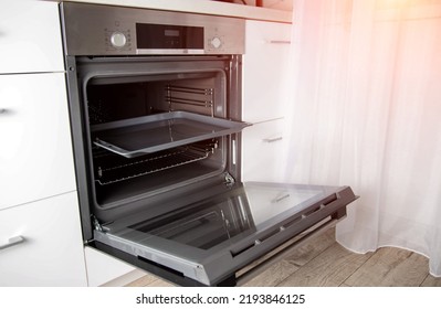 Modern electric oven with telescopic rails and steel baking tray. Hinged oven door. Black oven in a white kitchen. Automatic cooking program - Shutterstock ID 2193846125