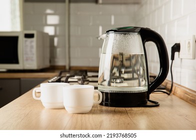 Modern electric transparent kettle on a wooden table in the kitchen.Kettle for boiling water and making tea.Home appliances for making hot drinks.Space for copy.Place for text.