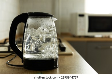 Modern electric transparent kettle on a wooden table in the kitchen.Kettle for boiling water and making tea.Home appliances for making hot drinks.Space for copy.Place for text.