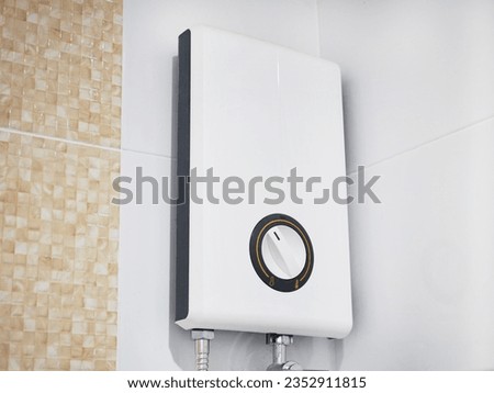 Modern electric water heater on the tile wall in the bathroom.