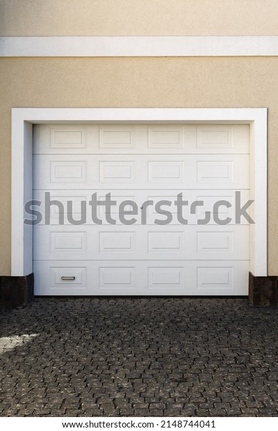 Modern electric white garage door in a traditional\
American house.