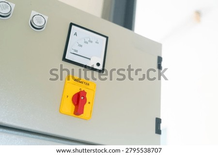 A modern electrical control panel with an analog ammeter and safety switch, designed for monitoring and managing electrical systems in industrial settings.