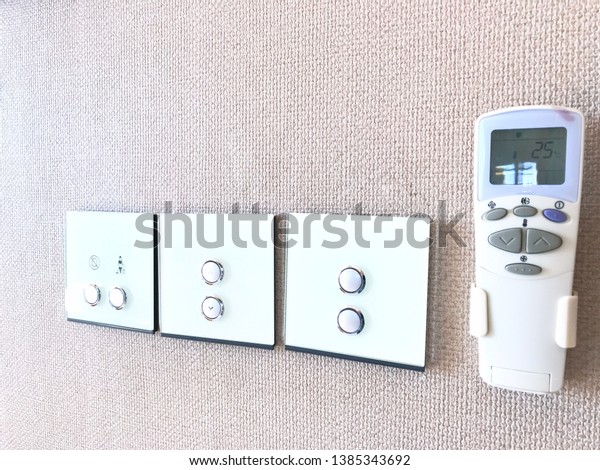 Modern Electrical switch and air conditioner\
remote control on gray wall background\
