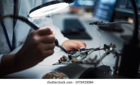 Modern Electronics Research, Development Facility: Female Engineer Does Computer Motherboard Soldering. Scientists Design PCB, Silicon Microchips, Semiconductors. Close-up Shot with Focus on Hands