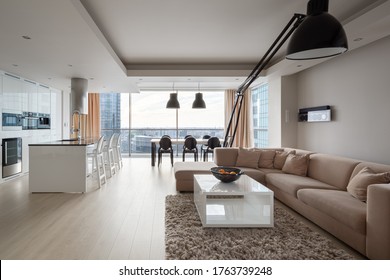 Modern And Elegant Apartment With Big Corner Sofa, Stylish Black Lamp, Luxury Kitchen Area And Dining Table In One Spacious Room With Big Window And Amazing City View