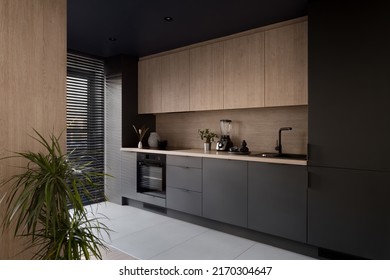 Modern and elegant kitchen, with black and wooden cupboards and big window with blinds