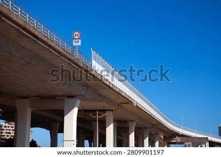 Modern Elevated Expressway Bridge with Reinforced Concrete Support, Reflective Noise Barrier and Speed Limit Sign Under Blue Sky