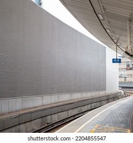 A Modern Empty Train Platform With No People In A Major City Transport Hub With A Platform Snaking Into The Background Bordered By A Concrete Wall Covered In A Silver Metallic Grille