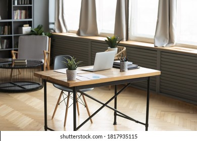 Modern Empty Wooden Table With Laptop And Green Plant On. Loft Home Workplace Of Freelancer Or Designer. Renovated Stylish Office Workspace Of Businessman In Apartment Or Flat. No People Around.