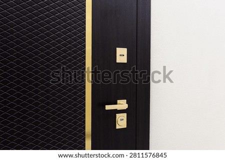 modern entry door combines dark wood grain with textured black diamond‑pattern panel. slim gold trim, handle, and lock add refined contrast