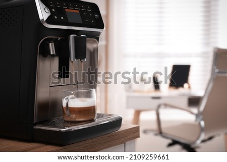 Modern espresso machine pouring coffee into cup in office. Space for text