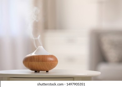 Modern essential oil diffuser on table indoors. Space for text