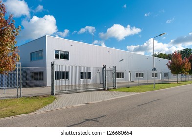 moderne Fassade eines Industriegebäudes, umgeben von einem Zaun mit Eisentor