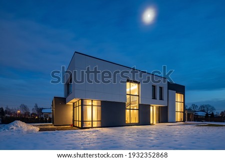 Modern exterior of luxury cottage. Private house in scandinavian style at winter evening.