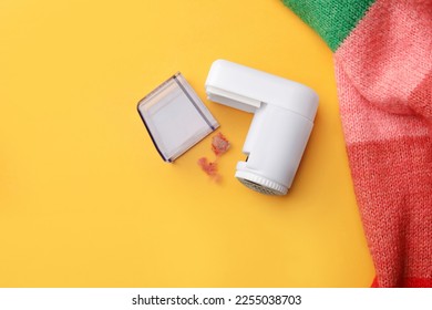 Modern fabric shaver and colorful knitted sweater on yellow background, flat lay. Space for text - Shutterstock ID 2255038703