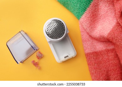 Modern fabric shaver and colorful knitted sweater on yellow background, flat lay - Shutterstock ID 2255038733