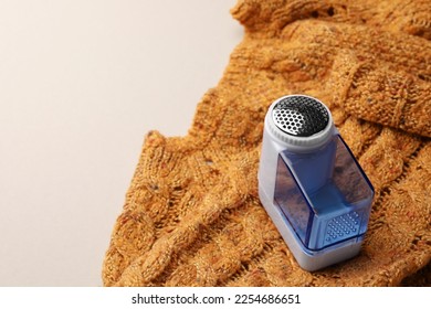 Modern fabric shaver and orange knitted sweater on white background, space for text - Shutterstock ID 2254686651