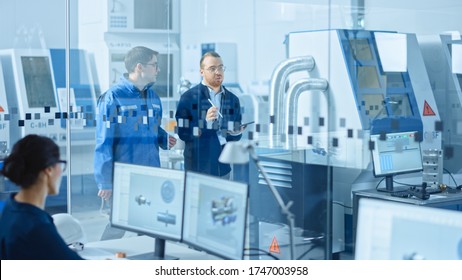 Modern Factory: Chief Industrial Engineer Walks With Workshop Supervisor, They Use Tablet Computer And Discuss Project Details. Manufacturing Facility With CNC Machinery And Robot Arm Assembly Line