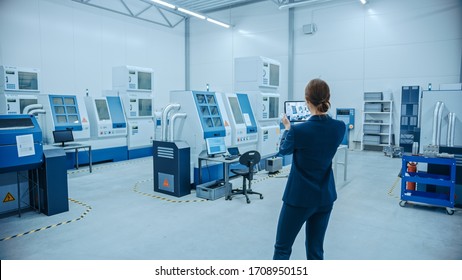 Modern Factory: Female Engineer Uses Digital Tablet Computer With Augmented Reality Software To Visualize Workshop For Room Mapping, Floor Layout. Facility With High-Tech CNC Machinery And Robot Arm